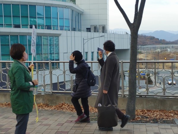 신천지인들이 손으로 얼굴을 가리며 시위현장을 지나가고 있다.